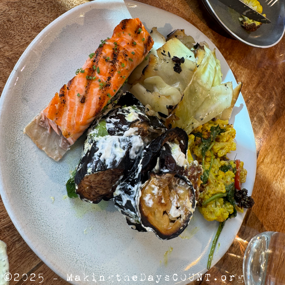A shared plate - salmon with dill sauce, roasted cabbage, eggplant with yogurt, and a turmeric tossed roasted cauliflower