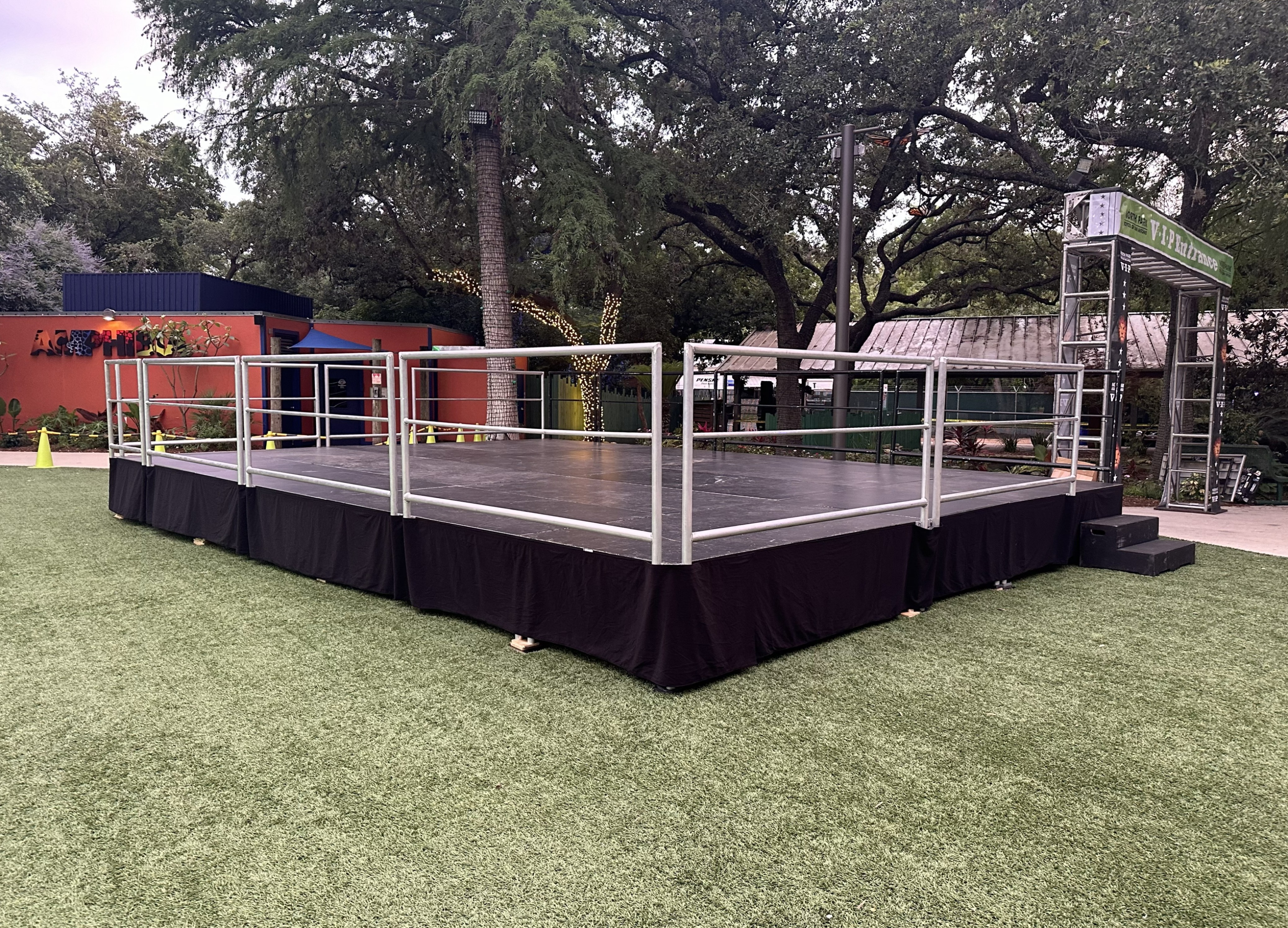 Aluminum bleachers set up beside an outdoor stage and filled with people
