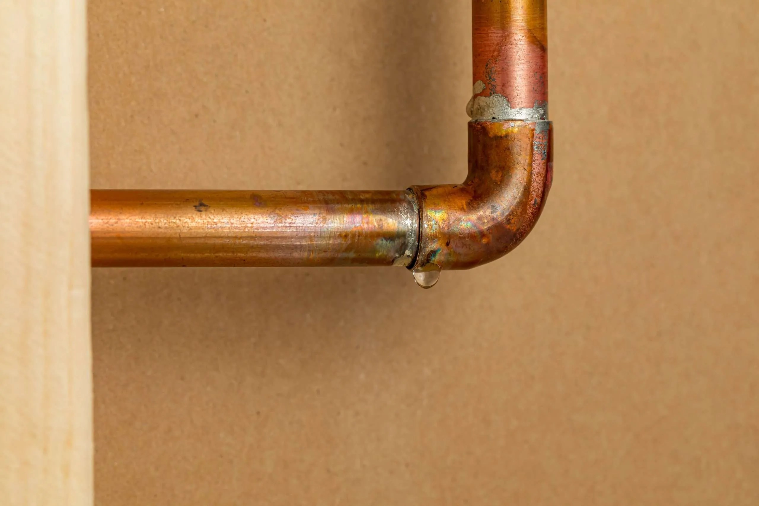 Copper plumbing pipe leaking water inside wall. Home repair, maintenance and remodeling concept.