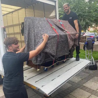 Furniture wrapped in blankets on the tail lift of a Mandy's Movers van
