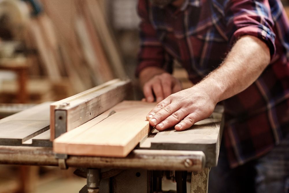 A man in a red shirt woodworking in his workshop