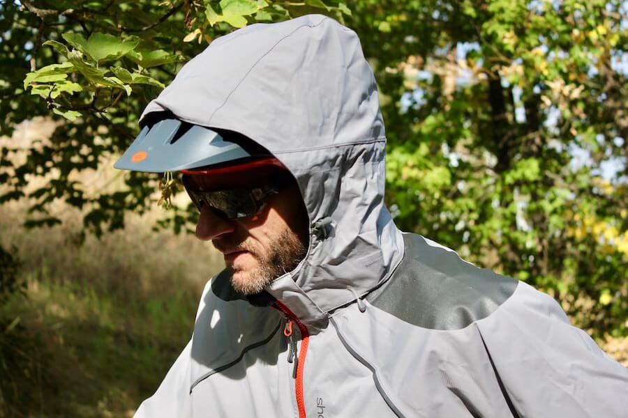 This photo shows the author wearing the Showers Pass Elements mountain biking rain jacket with the hood up.