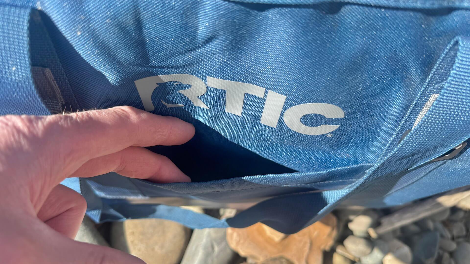 Author shows the exterior tuck pocket on RTIC insulated tote bag.