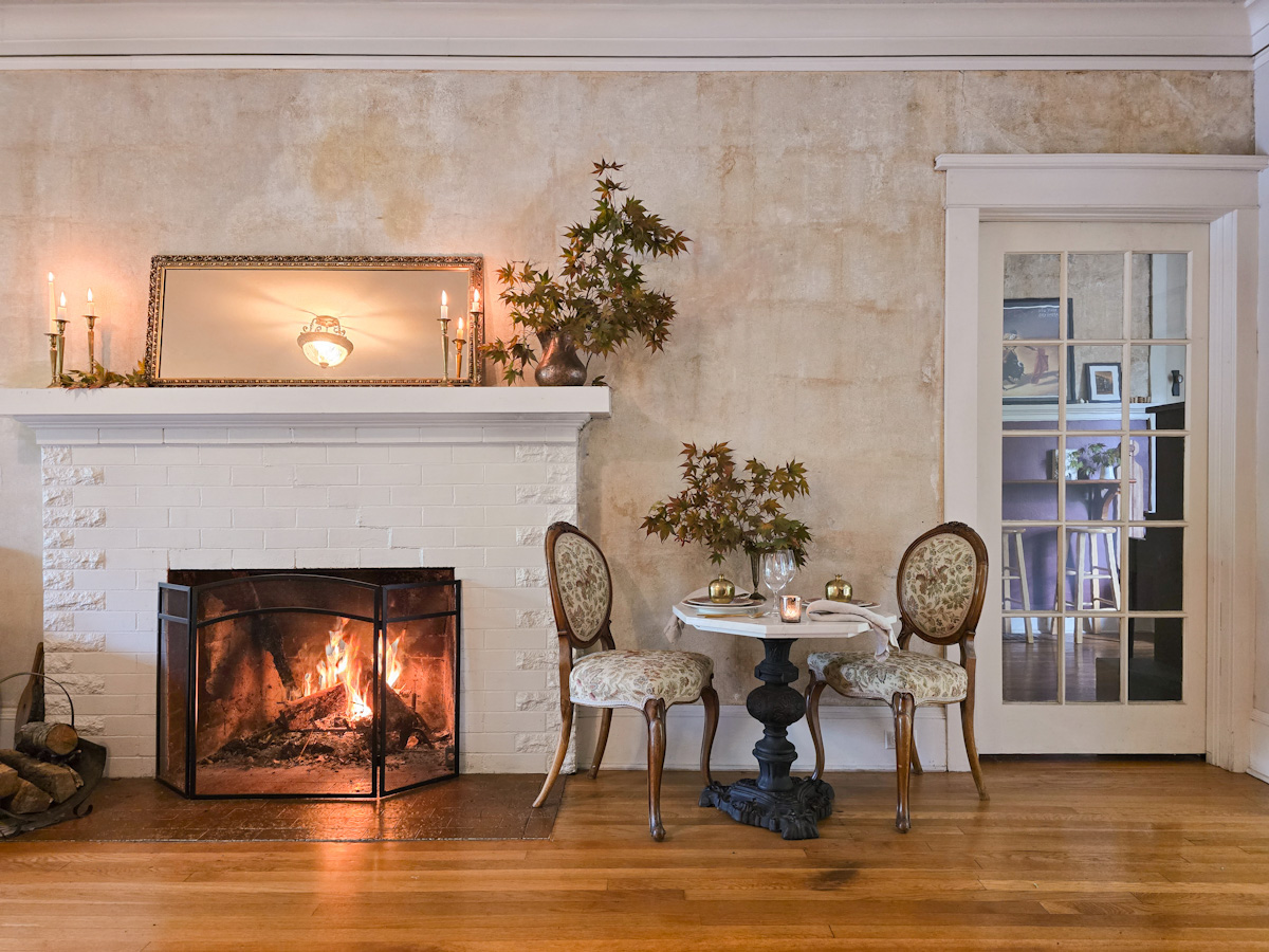 A neutral living room with a Fall table setting for two at a table next to the fire
