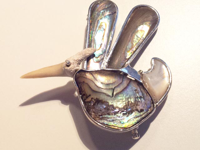 Brooch: a sharktooth from Mancora, Perù, decorated with a drop of silver for the eye, is the head of this strange fat pterodactylus. The wings come from a 19th century magnifying lens handle. The body, in mother of pearl, comes from New Zealand. The tail is a half moon of mother of pearl. The silver brings together these historic and geographically-varied pieces. Spilla: Pterodattilo: un dente di squalo proveniente da Mancora, Perù, ornato di un chiodino d’argento come occhio, formano la testa di questo panciuto pterodattilo. Le ali, in madreperla, ornavano il piccolo manico di un’antica lente di ingrandimento, il corpo in madreperla abalone viene dalla Nuova Zelanda. La coda, una mezza luna in madreperla bianca. L’argento assembla in un pezzo unico tutti questi frammenti che vengono da lontano.