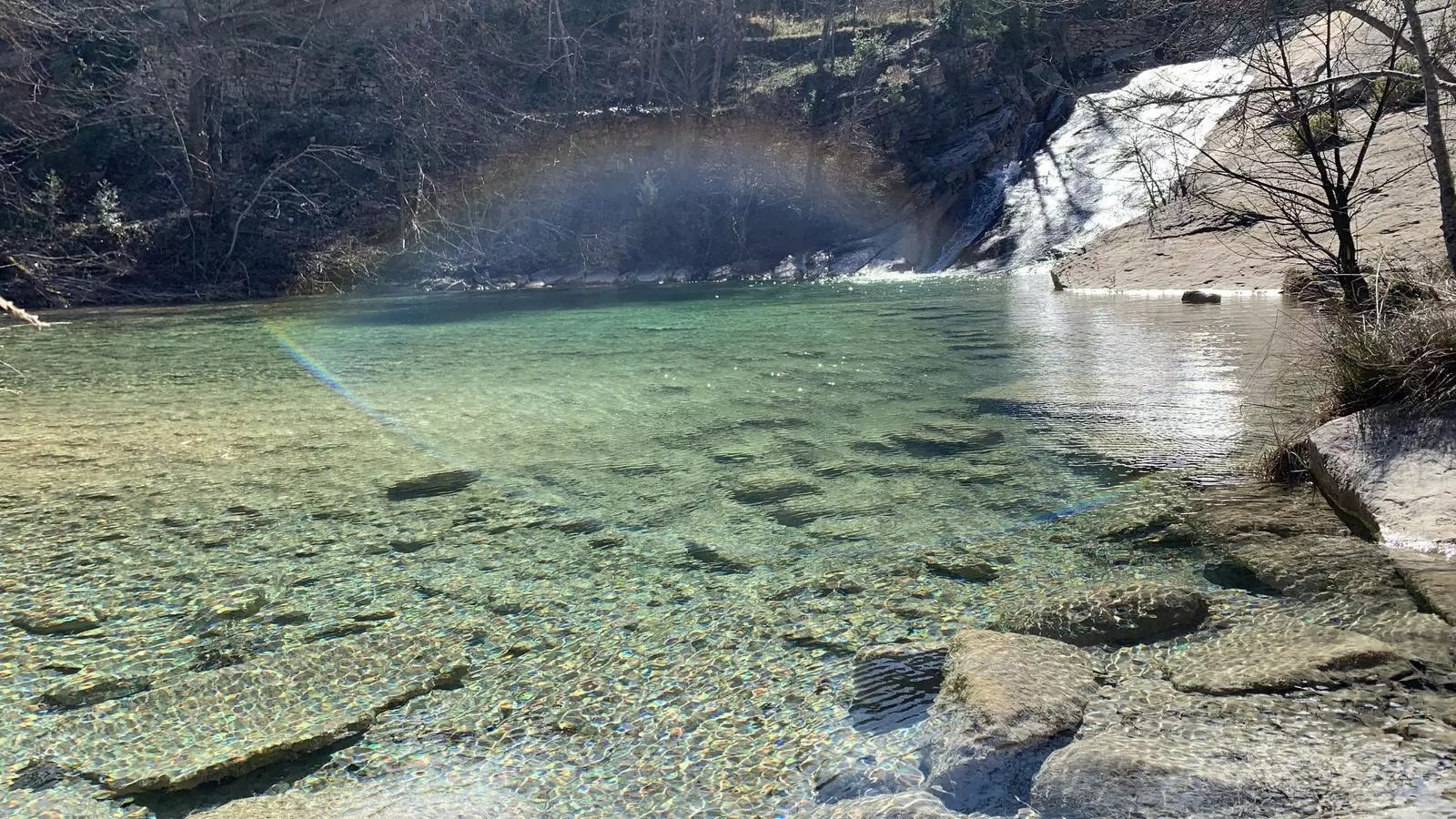 Poza de agua cristalina y cascada en Basses del Codó, con fondo rocoso y reflejos de luz en Coll de Nargó