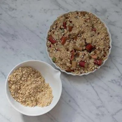 Den f&oslash;rste halvdel af crumbledejen er fordelt mellem rabarberstykkerne