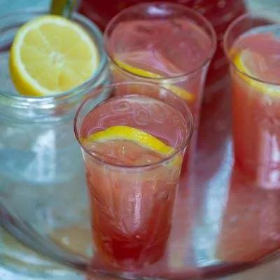 Glas med rabarberlemonade på en bakke: Man kan se citron og isterninger