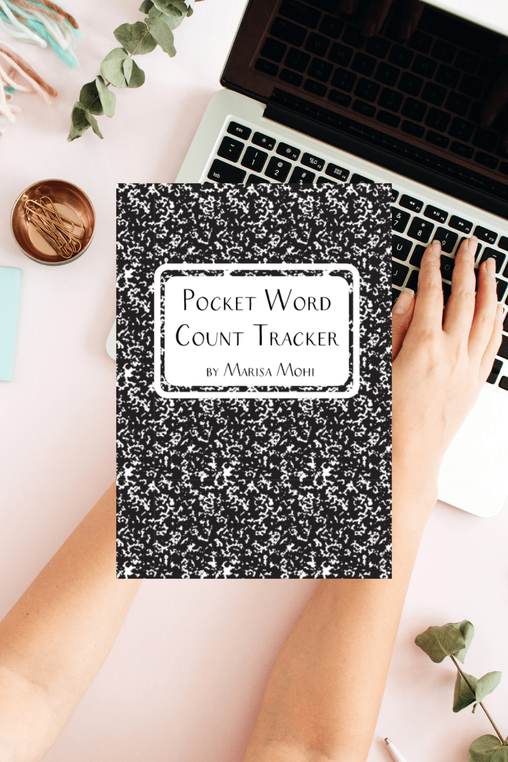 a light pink desk with a laptop and the cover of the Pocket Word Count Tracker