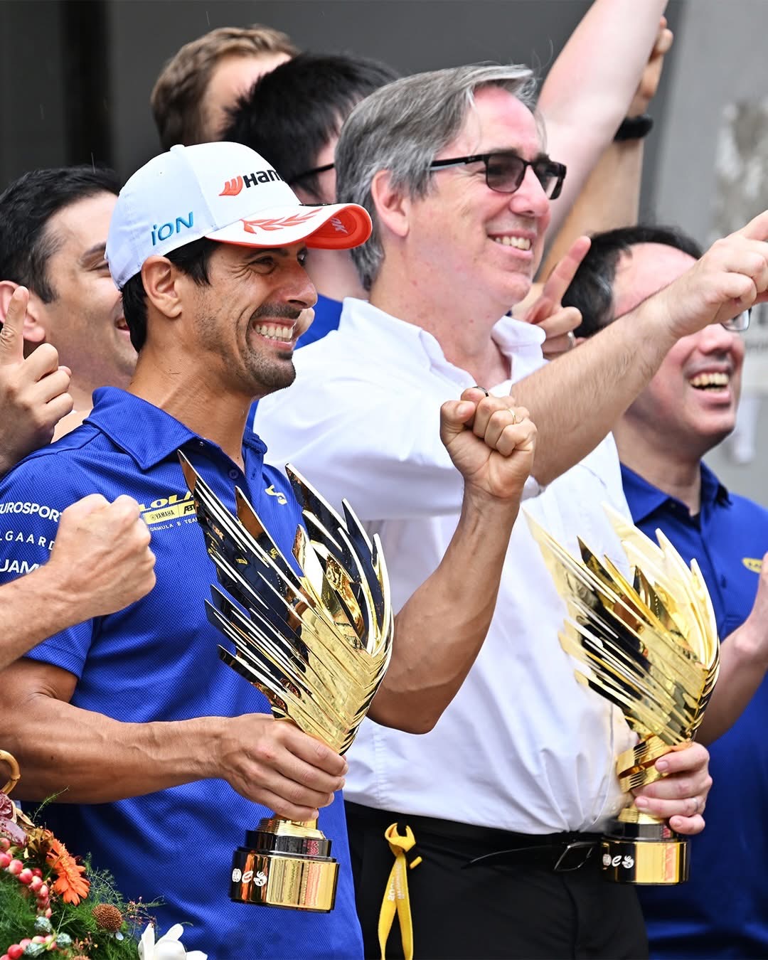 Mark Preston celebrating Lola Yamaha ABT’s Shanghai win with Lucas di Grassi and the team while holding a trophy.