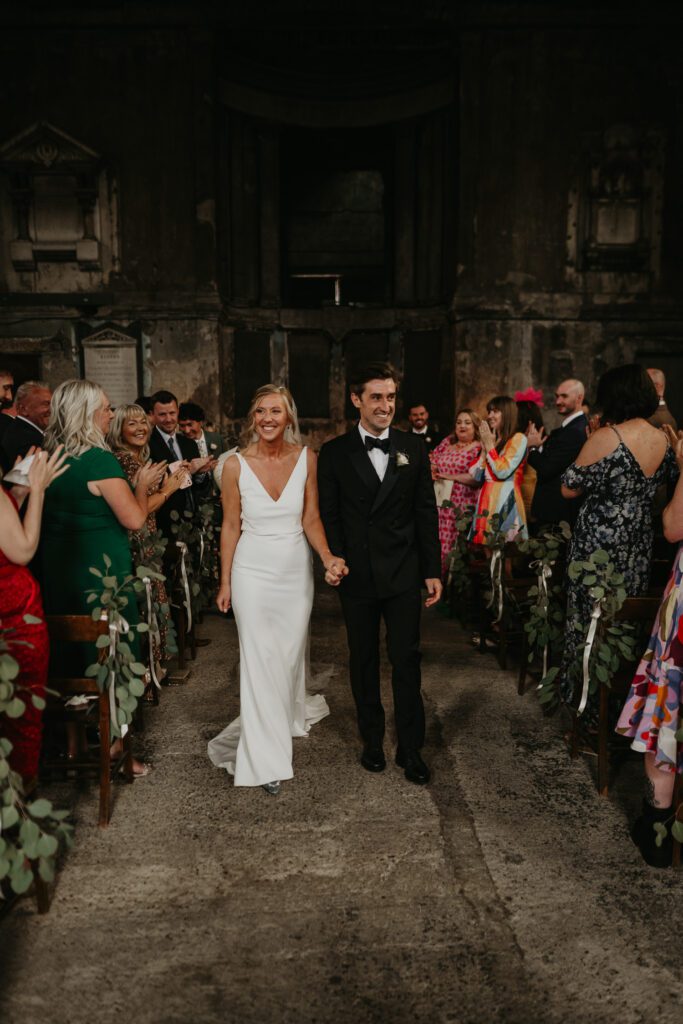 Bride and groom walk up the aisle at Asylum Chapel. 