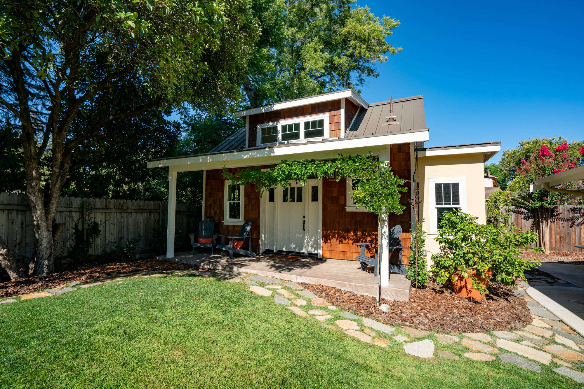 Detached art studio exterior with covered porch and mature landscaping