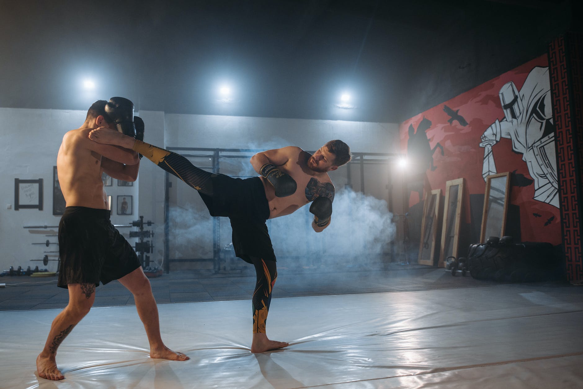 a shirtless man blocking his opponent s kick