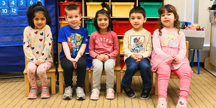 Little children sitting nicely on chairs in a row