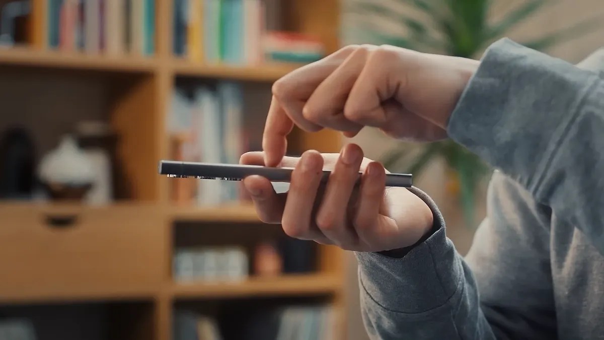 A person holding a phone in one hand and touching its screen with a finger.