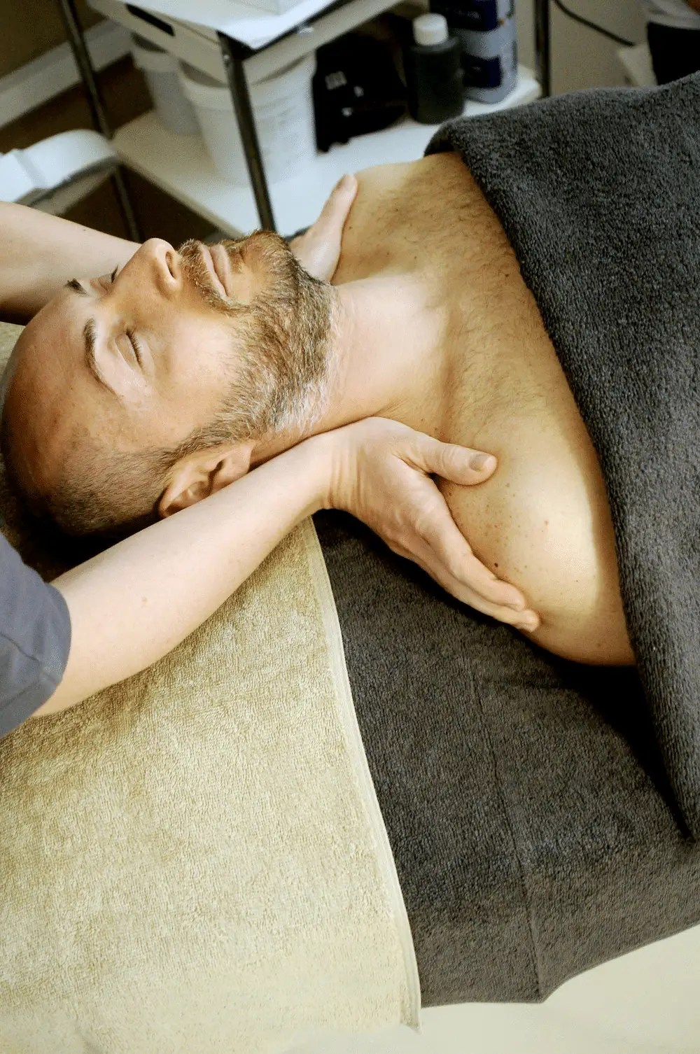 A man receiving shoulder massage for relaxation after a sports event