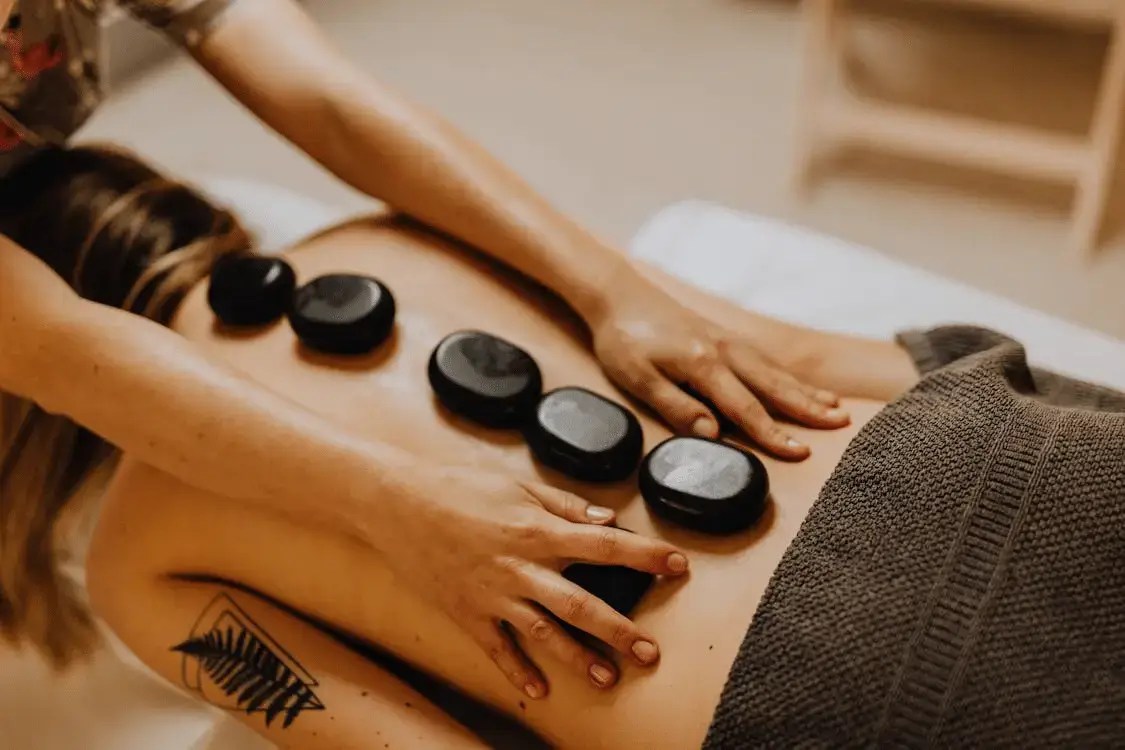 woman with a tattoo lying upside down with hot stones on her back
