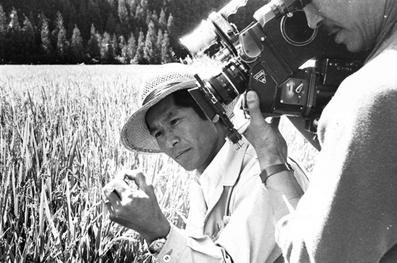 Old film still of a man holding a wheat grain while being filmed