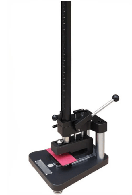 The image shows a tubular impact tester that applies rapid deformation impact using a falling-weight system during ASTM D2794 testing.