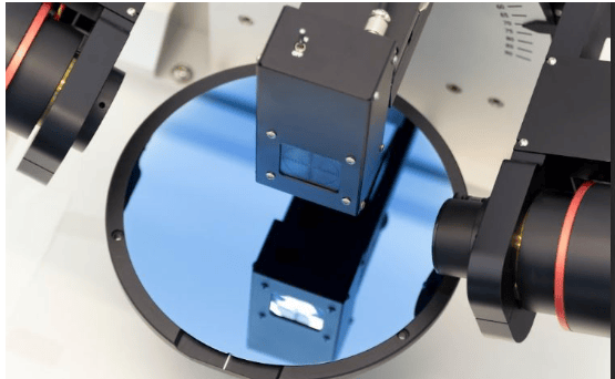  The image shows a photoelastic measurement system using polarized light to evaluate edge and surface stresses in flat glass according to ASTM C1279.