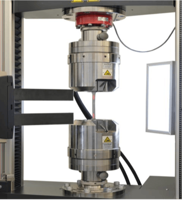 The image shows a universal testing machine that applies a controlled tensile load to composite specimens during ASTM D3039 testing.