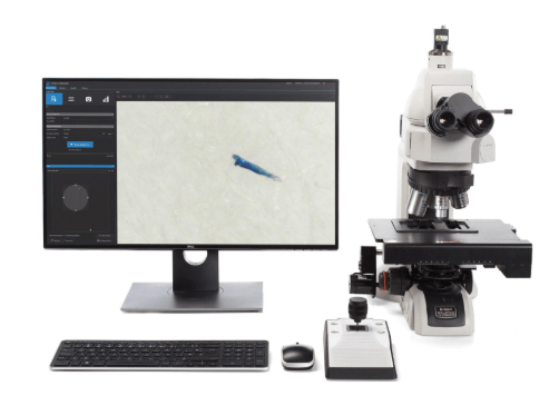 The image shows a laboratory setup with membrane filtration equipment, an optical microscope, and particle-counting instruments used for ASTM F24 surface cleanliness testing.