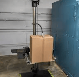 The image shows a drop test machine with a package for an impact test.