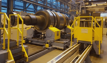 The image shows a digital ultrasonic flaw detector inspecting a large turbine steel rotor forging during ASTM A418 testing.