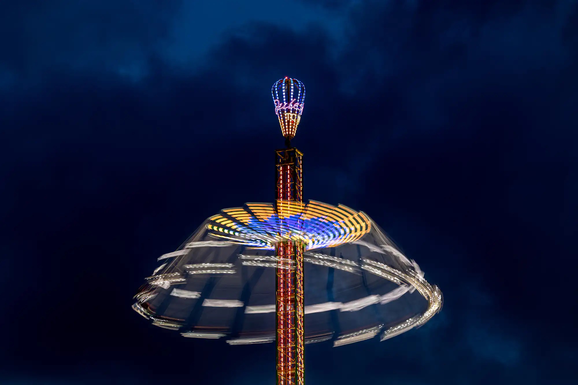 An amusement ride at night with a cloudy sky.