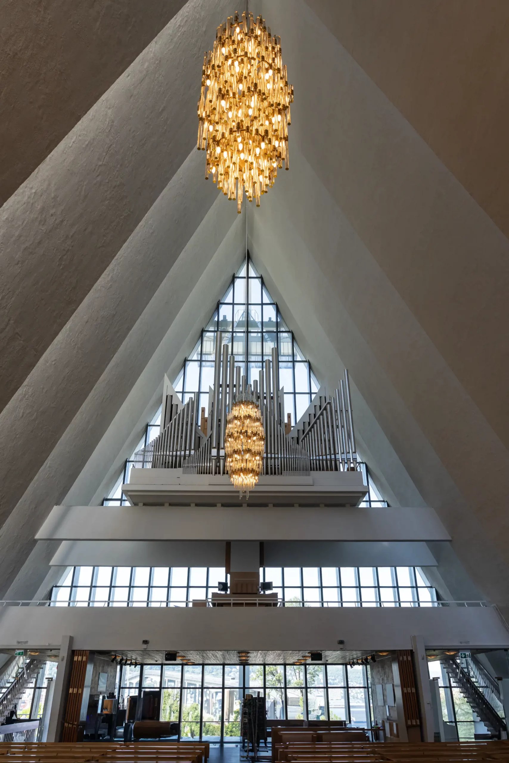 Innenraum der Eismeerkathedrale in Tromsø mit großen dreieckigen Fenstern, Orgel und zwei goldfarbenen Kronleuchtern