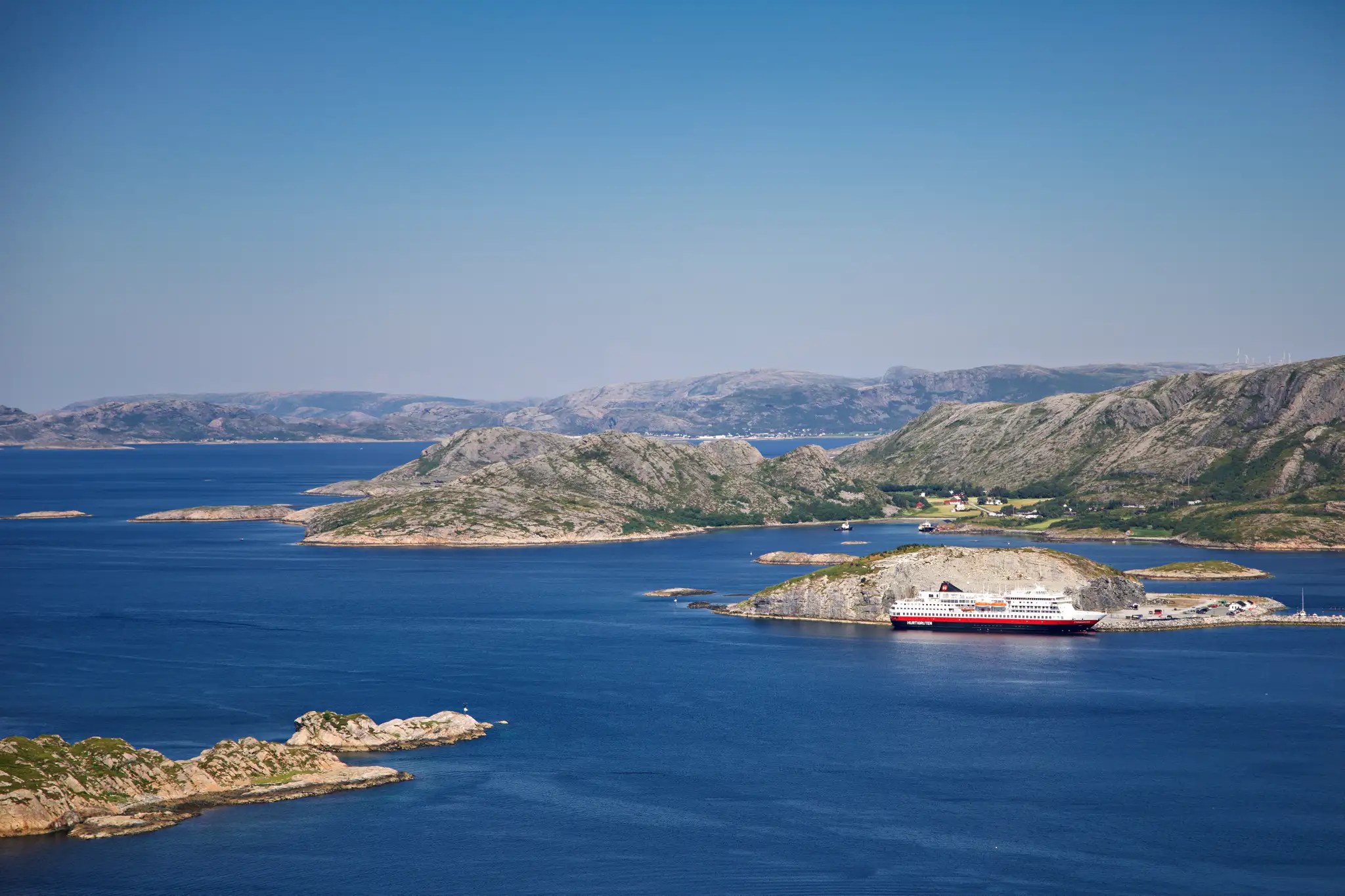 Kreuzfahrtschiff liegt im Hafen. Ruhiges Gewässer zwischen felsigen Inseln unter klarem Himmel