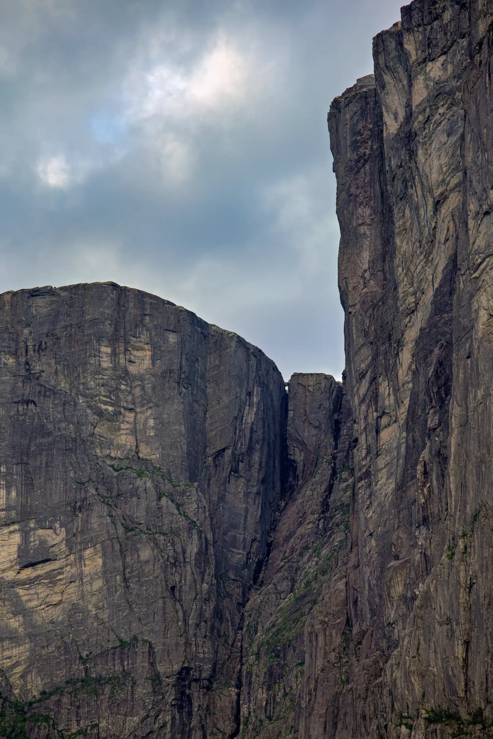 Hohe, steile Felswände mit einer schmalen Schlucht darunter unter bewölktem Himmel
