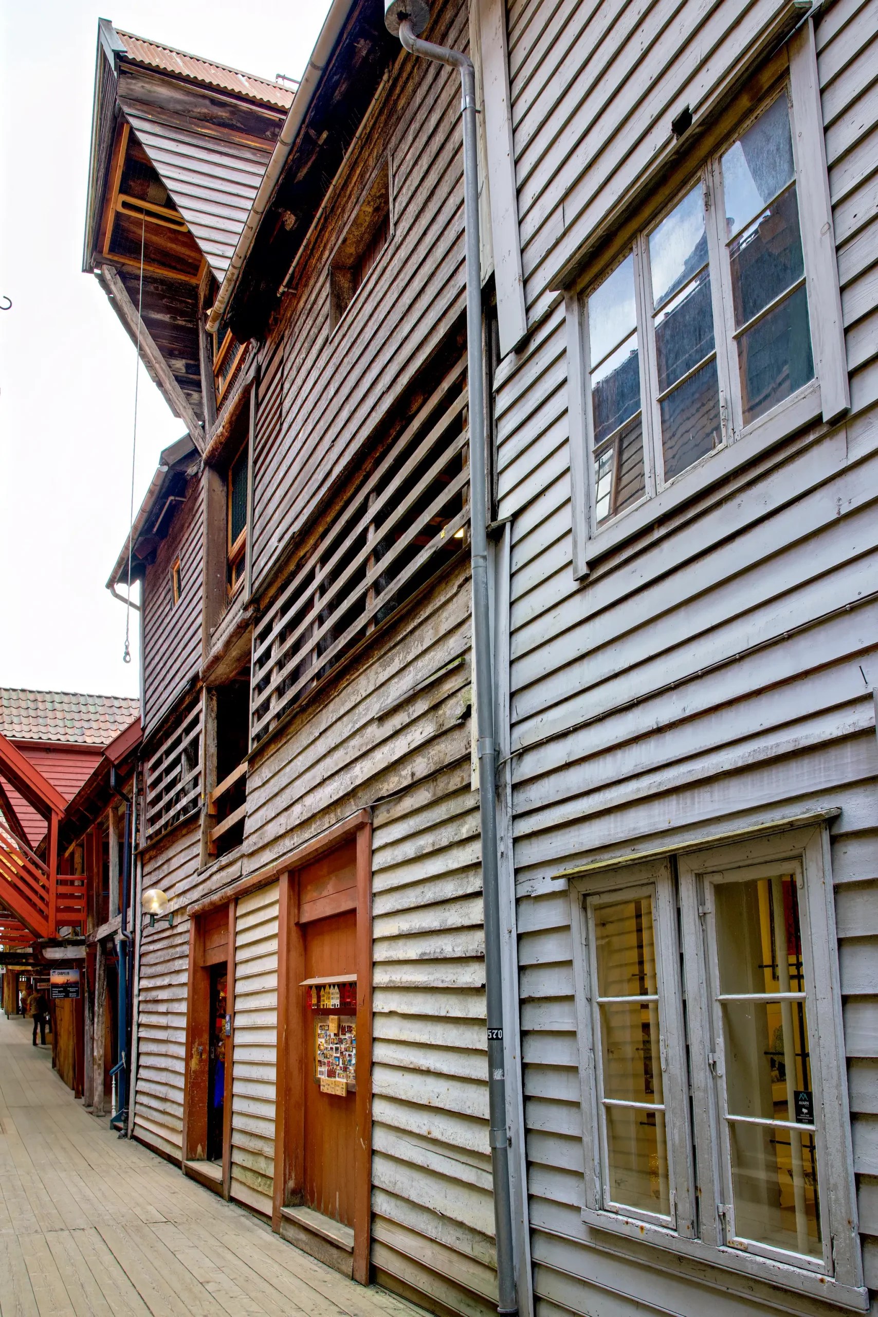 Enge Gasse mit traditionellen Holzhäusern in Norwegen, sichtbare Fenster und Türen