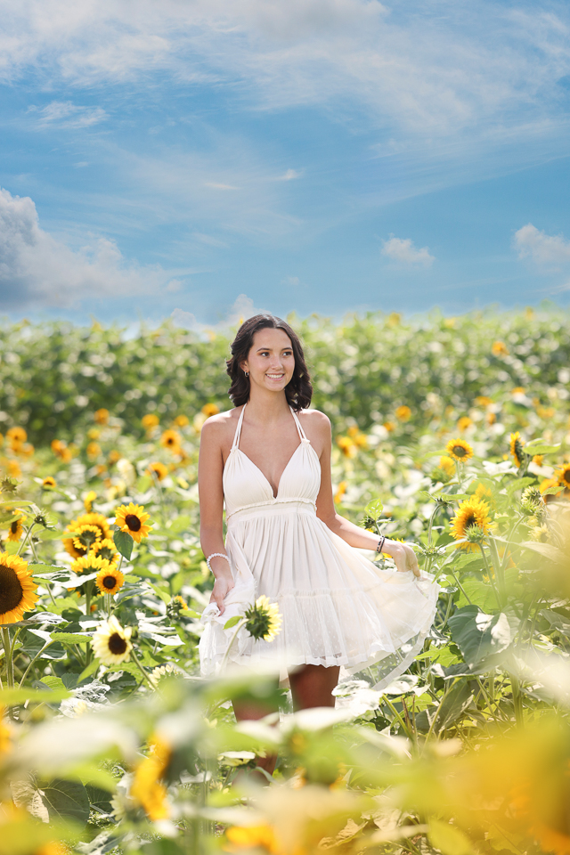 High school senior girl portrait in a sunflower field in Columbus, Ohio, smiling among the flowers.