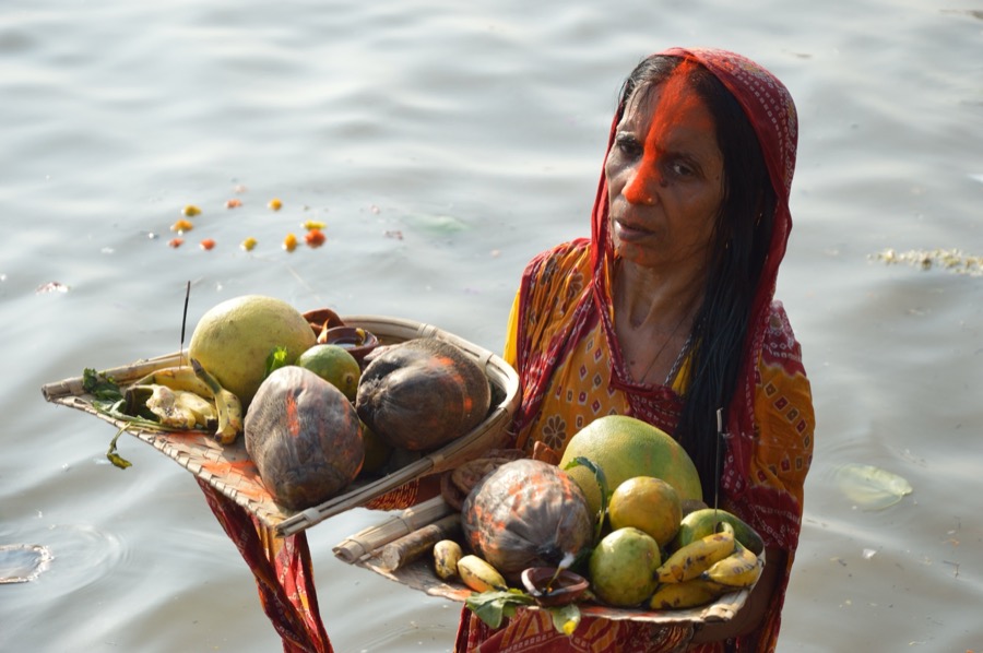 Devotee with offerings during Chhath Puja at a river ghat