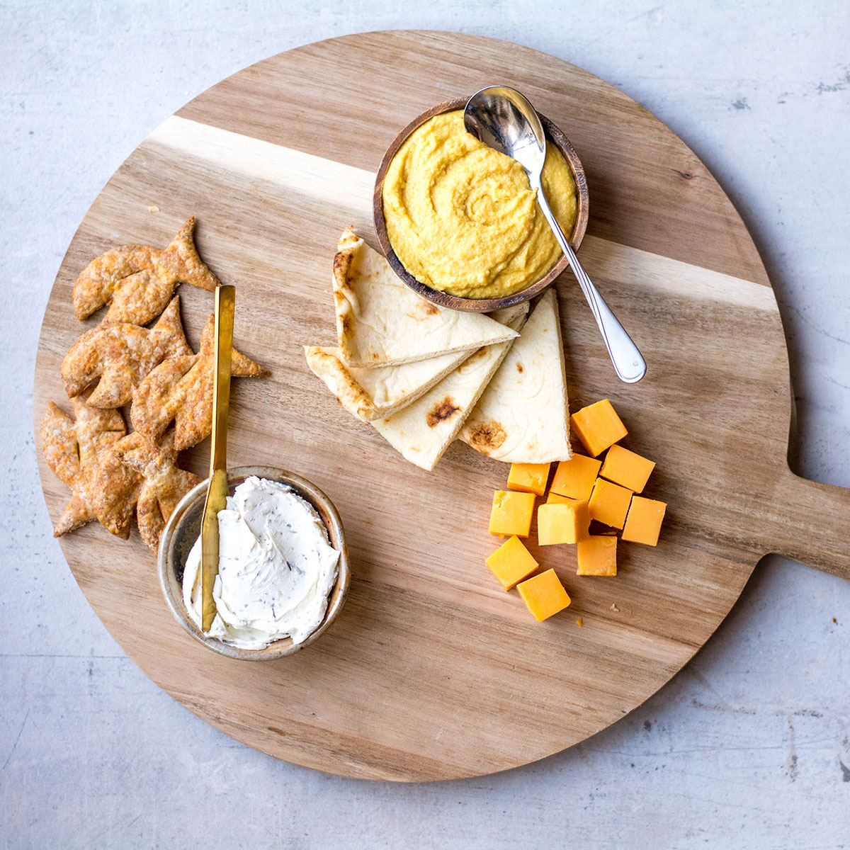 dips and cheese with pita on wooden platter