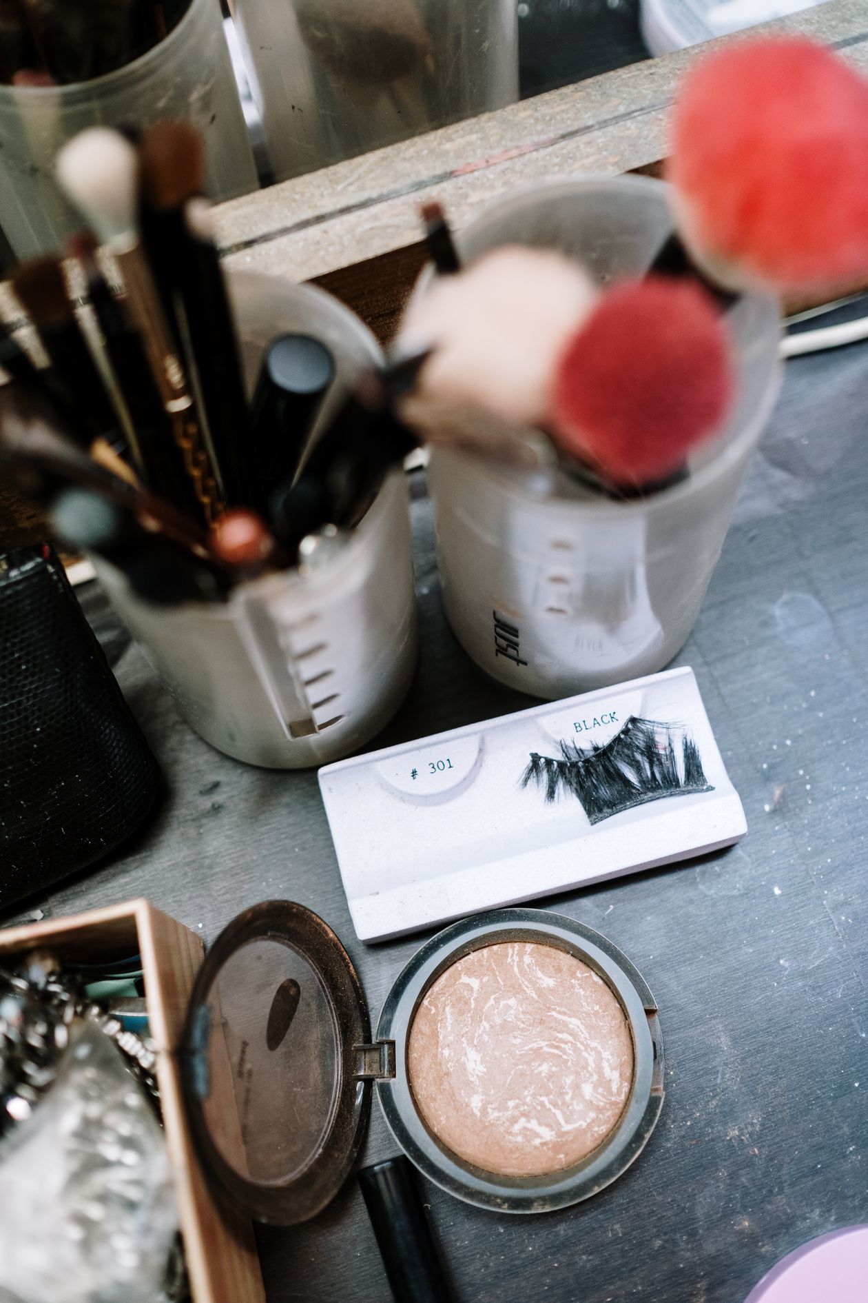 Makeup brushes, a powder compact and false eyelashes on a dressing table