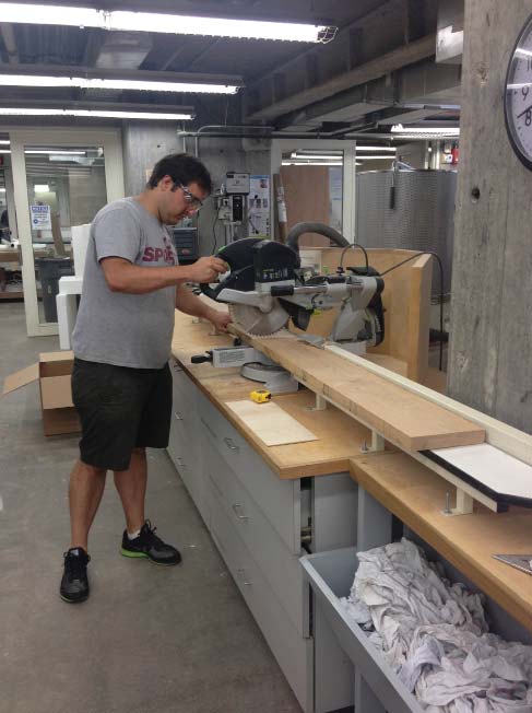 Carmine cutting down wood planks to uniform dimension.