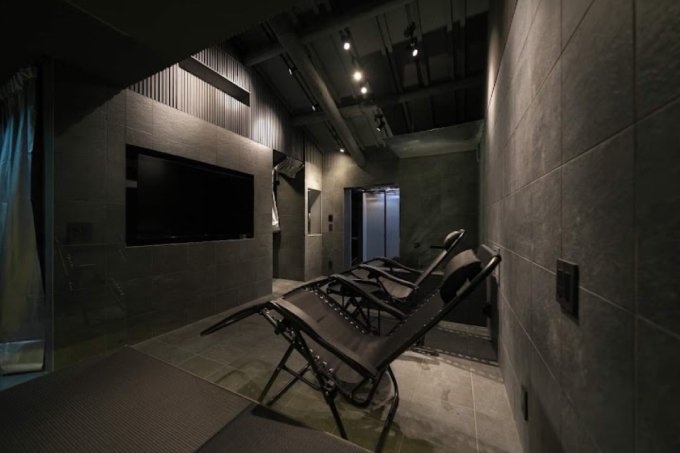 Dim modern home theater with a wall-mounted screen and three reclining chairs facing it
