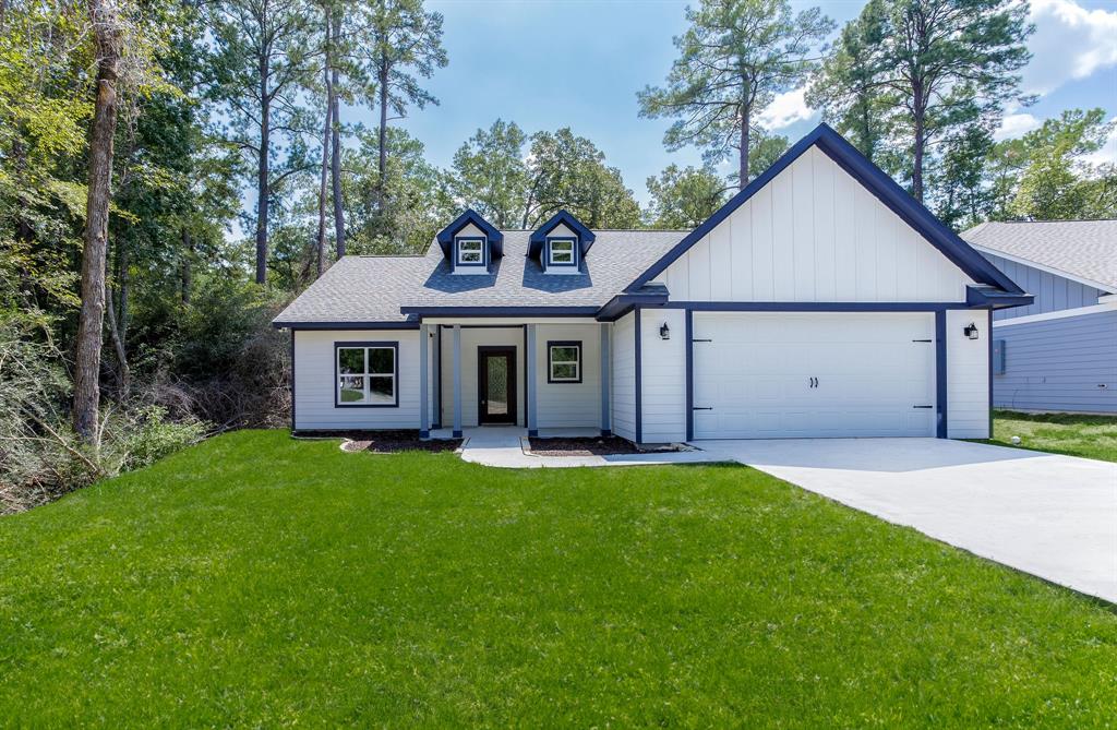 Front exterior of a white house with clean siding, black trim, and a neatly landscaped yard.