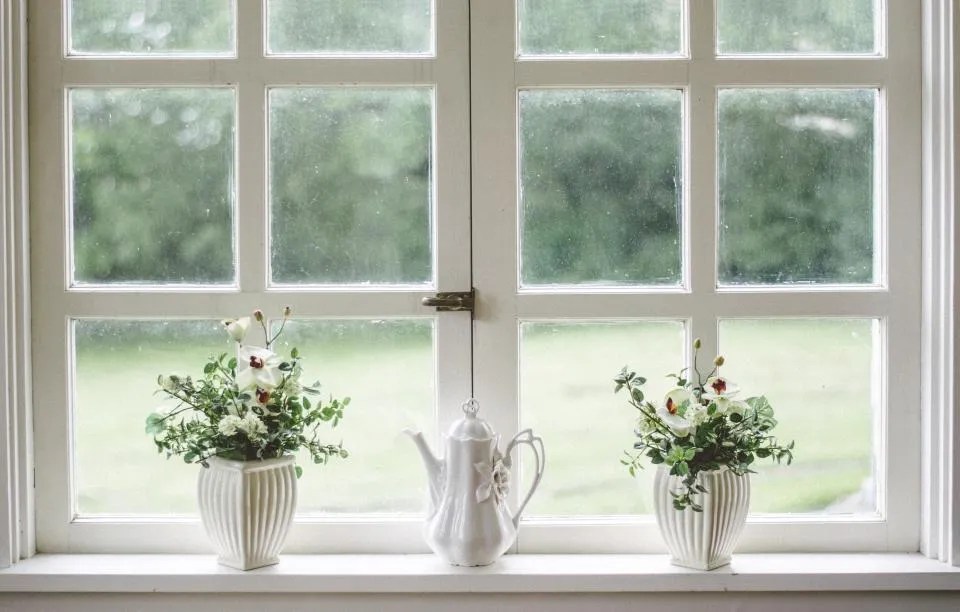 White-framed window with potted flowers on the sill, a source of fresh air for general salon ventilation