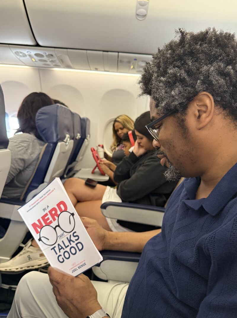 A man on an airplane reading Joel's book.