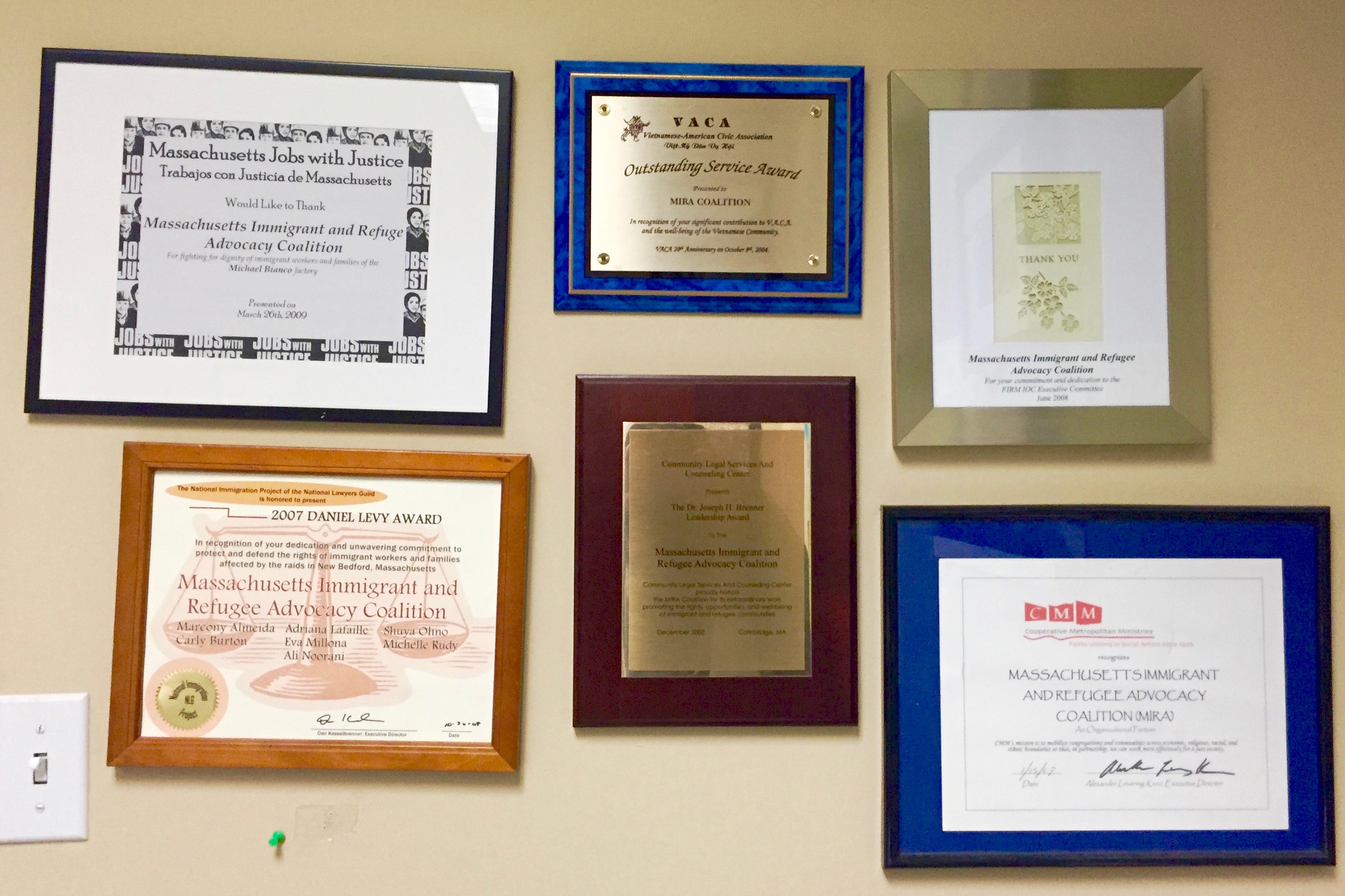 Certificates and awards for the MIRA Coalition hang together on a wall.