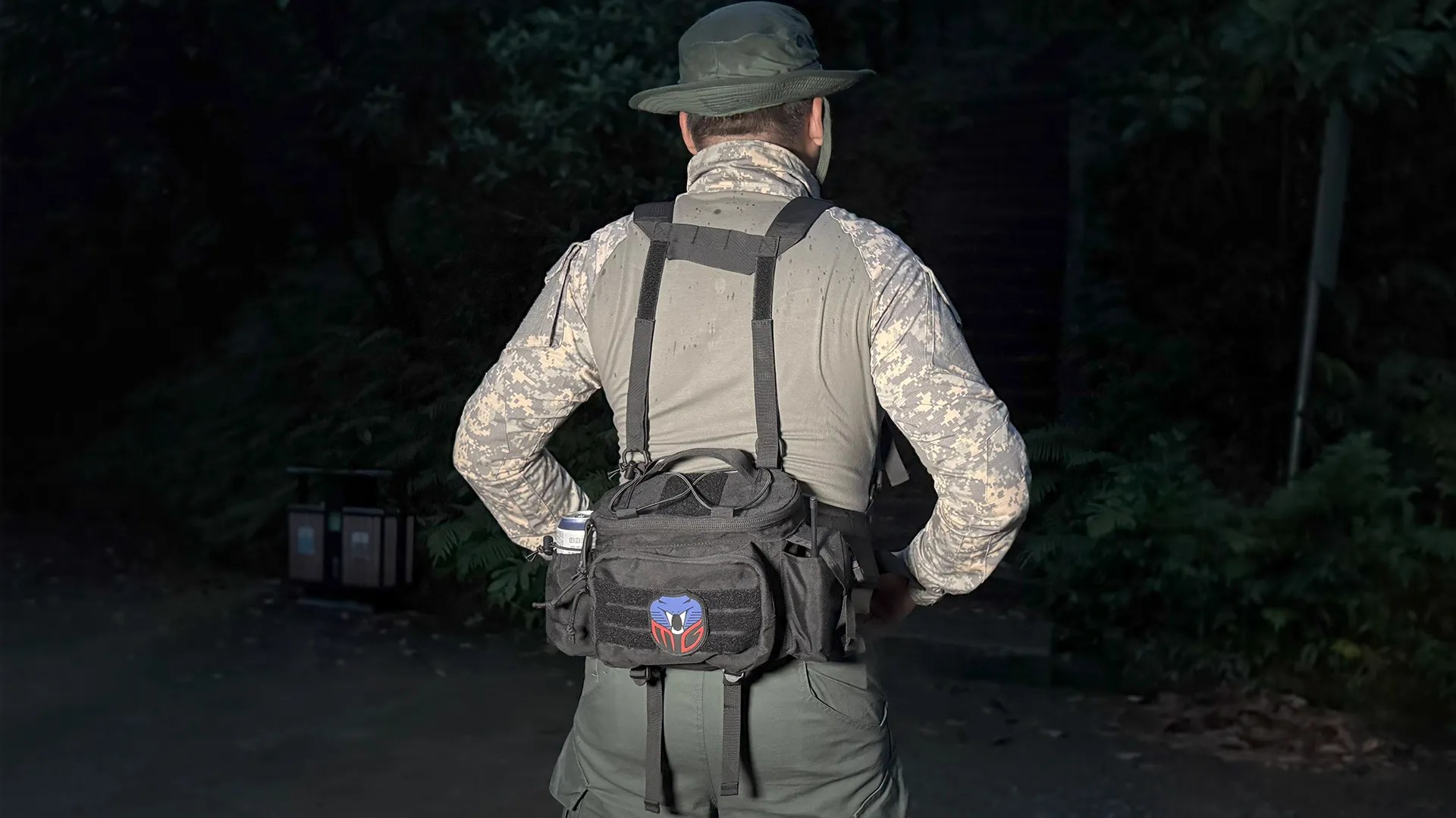 Man wearing a black tactical waist bag with harness in an outdoor setting