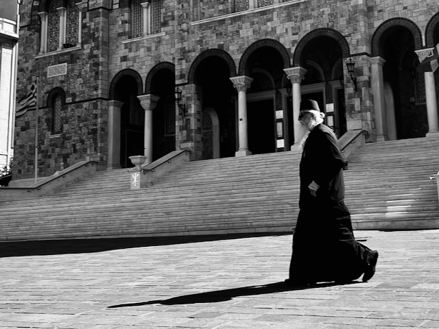 Ein Priester mit Sonnenbrille geht über den Kirchhof. in Athen. | Foto: Markus Hansen