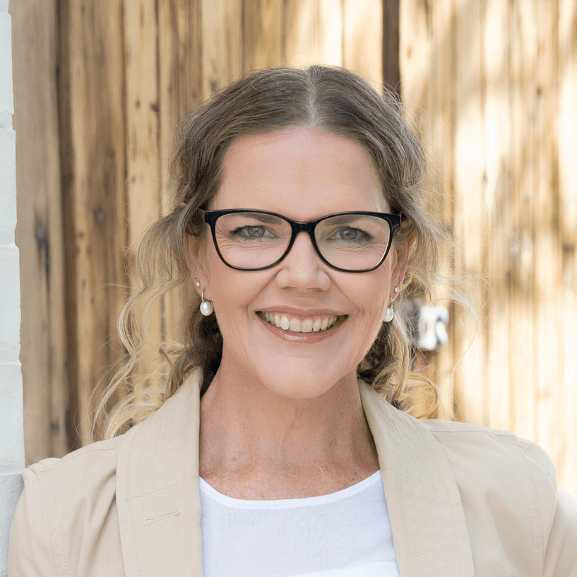 Michelle Daw, holistic psychologist, smiling in a beige blazer and glasses