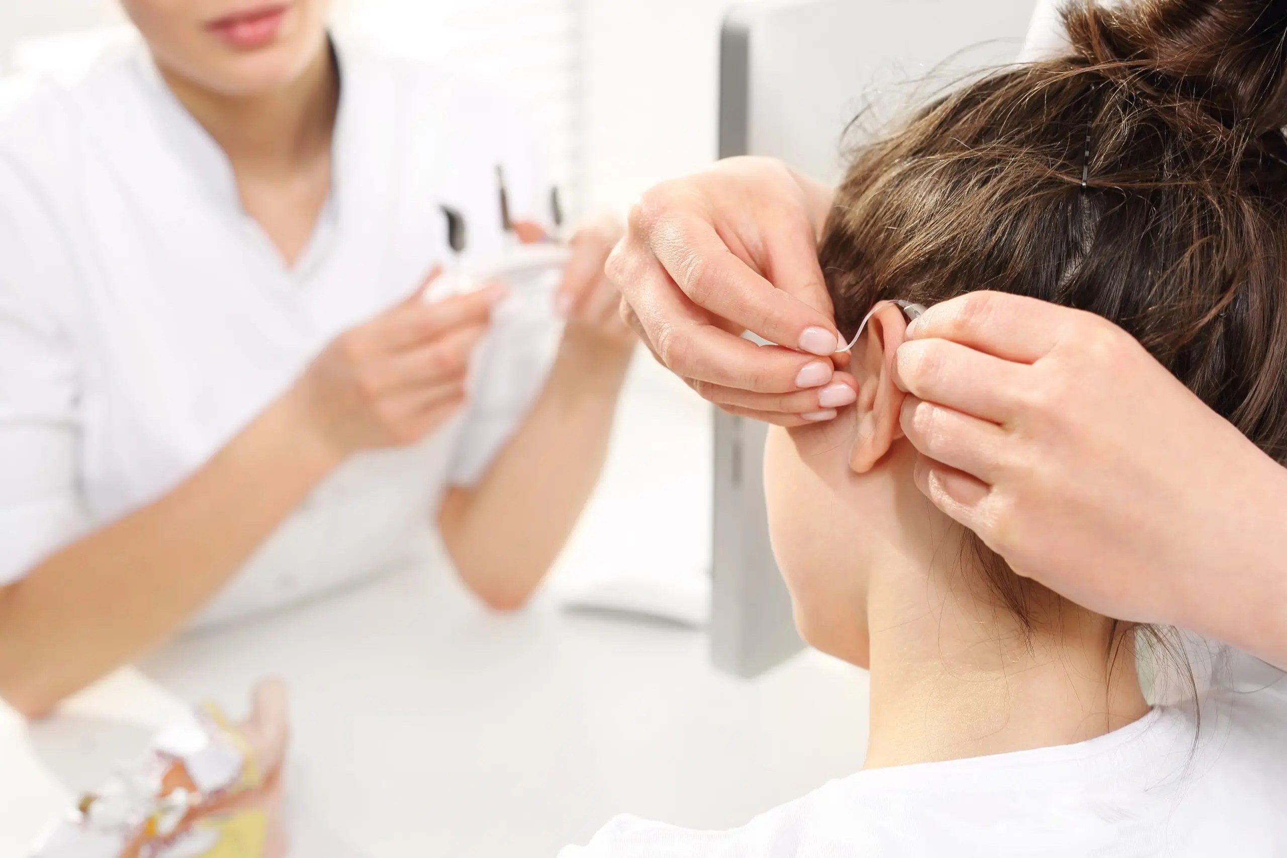 Doctor fitting a hearing aid.