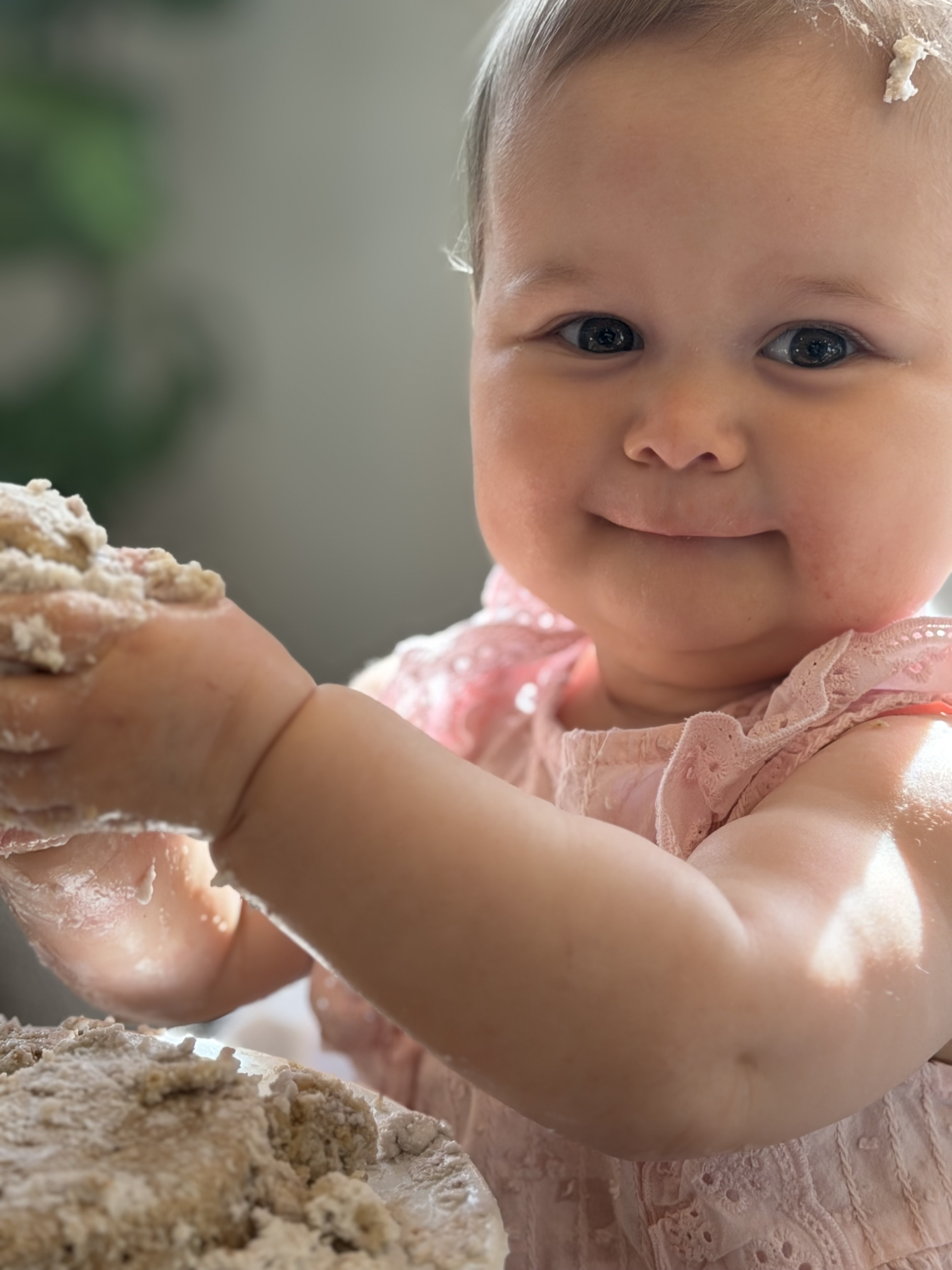Baby in a pink dress enjoying her birthday cake