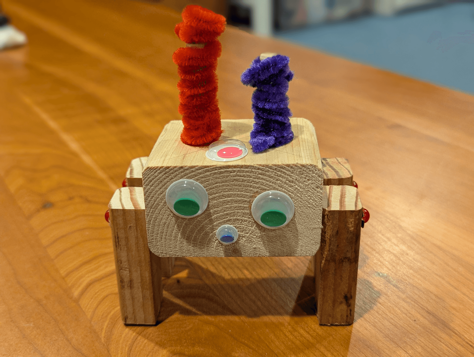 A goofy little guy made from wood blocks, metal fasteners, and fuzzy bits.