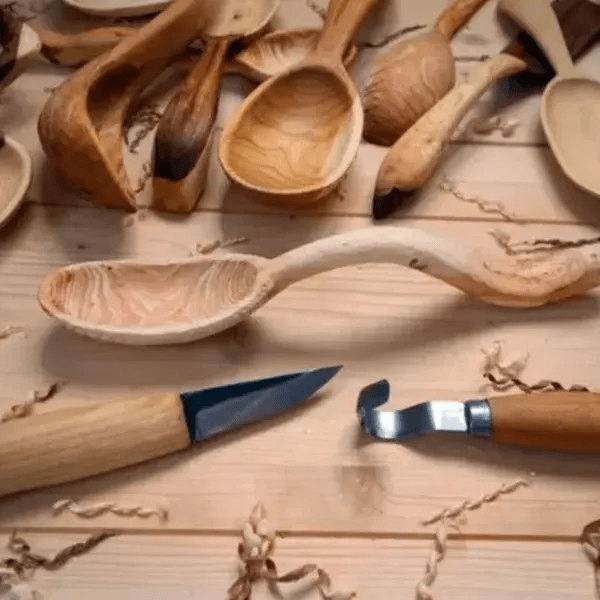 Carved wooden spoons with wood-handled carving tools.